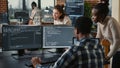 Mixed team of artificial intelligence cloud programers talking about programming in front of multiple screens