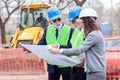 Mixed team of engineers meeting and discussing blueprints while visiting construction site site Royalty Free Stock Photo