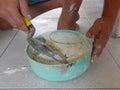 Mixed tile grout in a plastic bowl in a construction worker`s hands ready to be used for grouting ceramic tile floor - tiling work Royalty Free Stock Photo