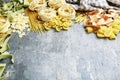 Mixed types and shapes of italian pasta on grey stone, background Royalty Free Stock Photo