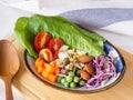 Mixed vegetable salad with tomato, corn, carrot, green peas, red cabbage, cos lettuce, granola, crispy coconut chips on oval plate Royalty Free Stock Photo