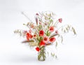 Mixed wild flowers bouquet and grasses in a glass vase. Poppy