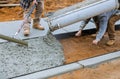 Truck operator pouring cement concrete casting on reinforcing metal bars of sidewalk Royalty Free Stock Photo
