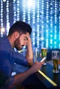 Mixing alcohol with messaging is a risky game. a young man looking upset while using his phone at a bar. Royalty Free Stock Photo