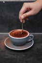 Mixing around hot cocoa chocolate in a grey cup with a metal spoon