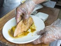 Mixing the chicken breast evenly with marinade at the kitchen. Hands with plastic cover for hygiene purposes