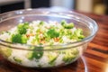 mixing chopped broccoli with rice in glass bowl