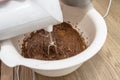 Mixing the dough with a hand mixer with a whisk with melted butter added, the dough is in a thick liquid brown mass.