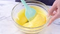 Mixing egg yolk into cake batter with green rubber spatula mixer tool stirring until smooth and blend well in a glass bowl, close