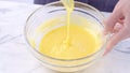 Mixing egg yolk into cake batter with green rubber spatula mixer tool stirring until smooth and blend well in a glass bowl, close