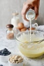 Mixing eggs, flour and milk in bowl. Concept of Cooking ingredients and method on white marble background, Dessert recipes and