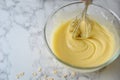 Mixing eggs, flour and milk in bowl with silver wire whisk. Concept of Cooking ingredients and method on white marble background,