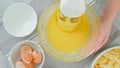 Mixing eggs and sugar in a glass bowl, view from above, woman hands. Apple cake recipe