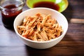 mixing shredded chicken with bourbon bbq sauce in bowl