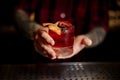 Mixologist holding a glass of strong fresh whiskey cocktail