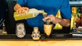 Mixologist making Yuzu cocktail with Shaker, Double Size Jiggers and drinking glass with ice cube on cocktail counter bar