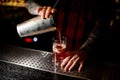 Mixologist pouring sweet juicy cocktail into a glass on bar