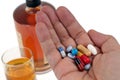 Mixture of drugs in a hand with a glass and a bottle of alcohol in the background Royalty Free Stock Photo