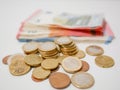 Mixture of Euro coins and banknotes lying on a white desk. Notes and coins of various denominations.