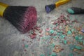 A mixture of eye shadows and applicators crumbled on a rustic steel table. Confusing jumble of cosmetic products