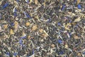 A mixture of green tea leaves and dried additives: cornflower petals, mango fruit, lemongrass, rose petals, and calendula petals