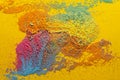 Mixture of multicolored powder is scattered randomly on a yellow background. Copy space. Abstract texture. Top view.