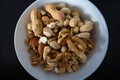 Mixture of nuts peanuts, pistachios, almonds, walnuts, hazelnut, cashew in a bowl from top view with black background Royalty Free Stock Photo