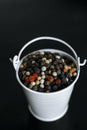 A mixture of pepper varieties with peas in the decorative little white bucket on the black background. Heap of various