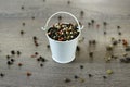 A mixture of pepper varieties with peas in the decorative little white bucket on the wooden background. Heap of various