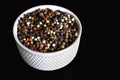 A mixture of pepper varieties with peas on the white plate on the black background. Heap of various pepper. Mix of red