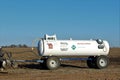 MKC Anhydrous Ammonia tank behind an implement in a farm field out in the country with blue sky in Kansas. Royalty Free Stock Photo
