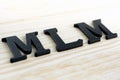 MLM (or Multi-Level Marketing) letters on wood background Royalty Free Stock Photo