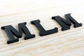 MLM (or Multi-Level Marketing) letters on wood background