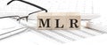 MLR - Minimum Loan Rate written on wooden cube with keyboard , calculator, chart,glasses.Business concept