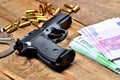 9mm pistol - handgun, handcuffs, bullets and euro banknotes on old wooden table Royalty Free Stock Photo