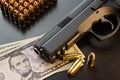 Semi-automatic pistol and bullets on dollar banknotes laid out on black table Royalty Free Stock Photo