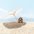 Mminiature house under beach umbrella on seashore on background of blue sky and sea. Square size. Copy space Royalty Free Stock Photo