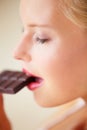 Mmm, what amazing flavor. Young woman enjoying a delicious piece of chocolate - side view.