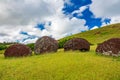 Moai pukaos on the ground under cloudy sky