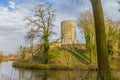 Moat with calm water with the tower of the Stein castle ruins on a hill, bare trees, climbing plants