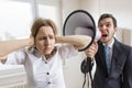 Mobbing at work. Manager is shouting at his secretary at work with megaphone Royalty Free Stock Photo