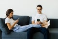 Mobile addiction concept, young couple ignoring each other using smartphones relaxing on sofa