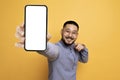 Mobile Advertisement. Cheerful Asian Man Pointing At Big Blank Smartphone In Hand