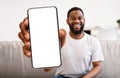 Mobile Advertisement. Cheerful Black Man Holding Blank Smartphone With Big White Screen