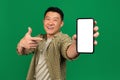 Mobile app advertisement. Happy asian mature man pointing at empty smartphone screen, mockup