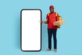 Mobile App. Black Delivery Guy Holding Pizza Boxes Pointing At Blank Phone Royalty Free Stock Photo