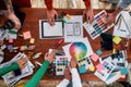 Mobile app design. Top view of designers discussing sketches, choosing colors from palettes lying on the desk while Royalty Free Stock Photo