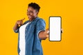 Excited African Woman Showing Phone Screen Recommending Application, Yellow Background