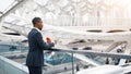 Mobile Banking. Black Man With Smartphone And Credit Card Standing At Airport Royalty Free Stock Photo