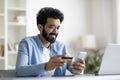 Mobile Banking. Smiling Indian Man Using Smartphone And Credit Card In Office Royalty Free Stock Photo